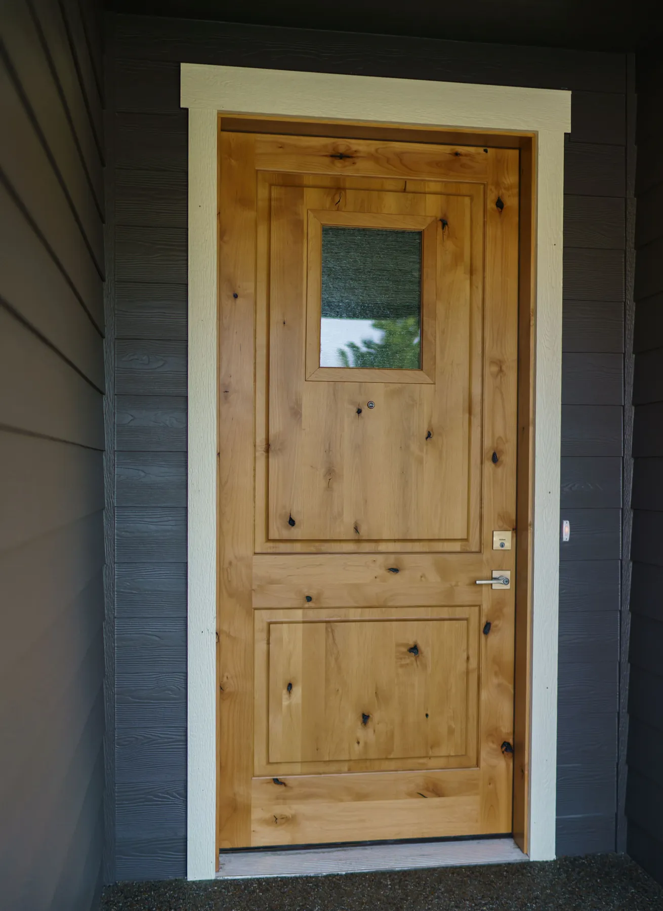 Stained wood entry: Knotty wood door with a glass lite, cased in painted trim.