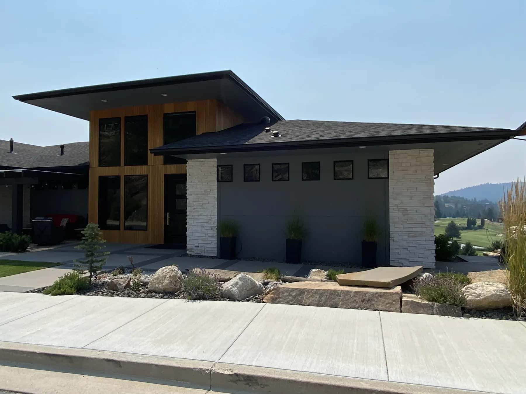 Modern prairie home with deep overhangs and a white stone wall