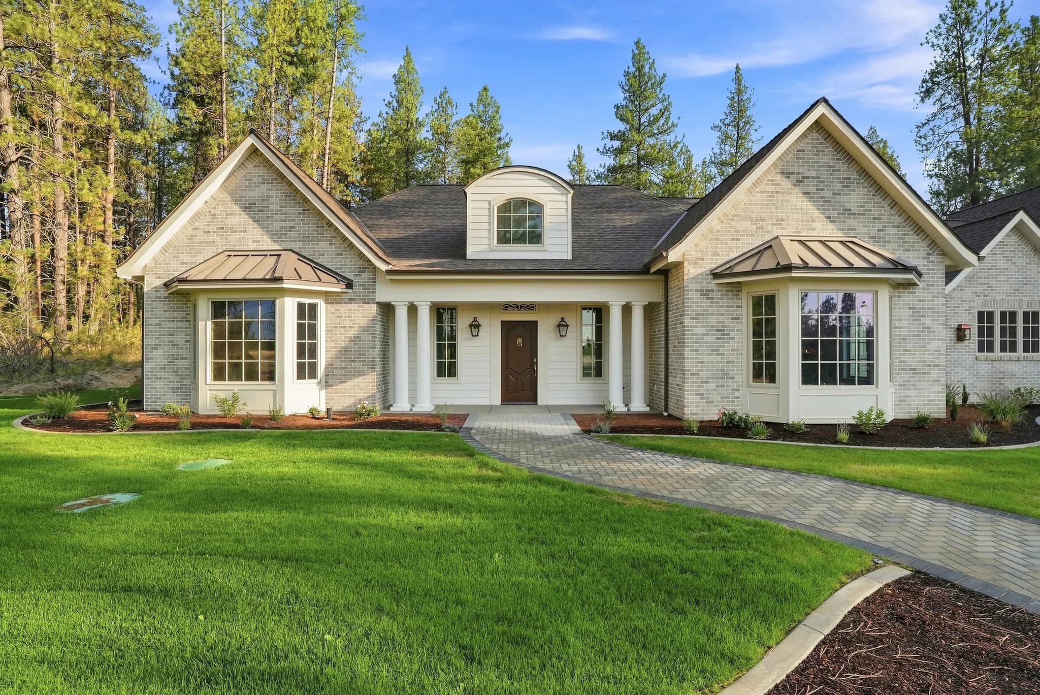 Painted-brick French country home with copper-roofed bays, fully custom by JM Homes