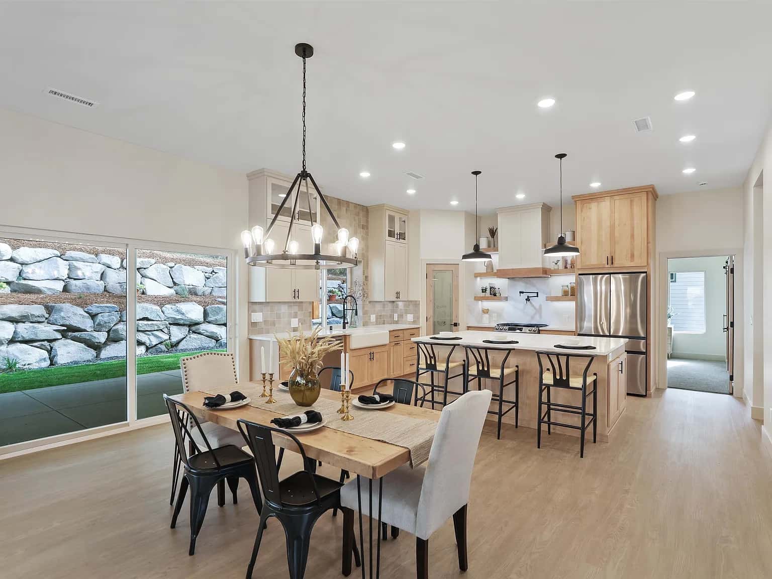 Open kitchen and dining room with a maple island, farmhouse sink and wagon-wheel chandelier
