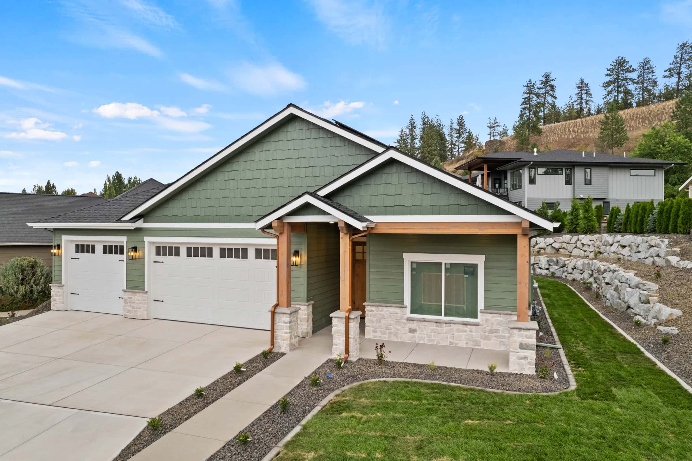 Craftsman front porch with stone bases and boulder terraces on a hillside lot