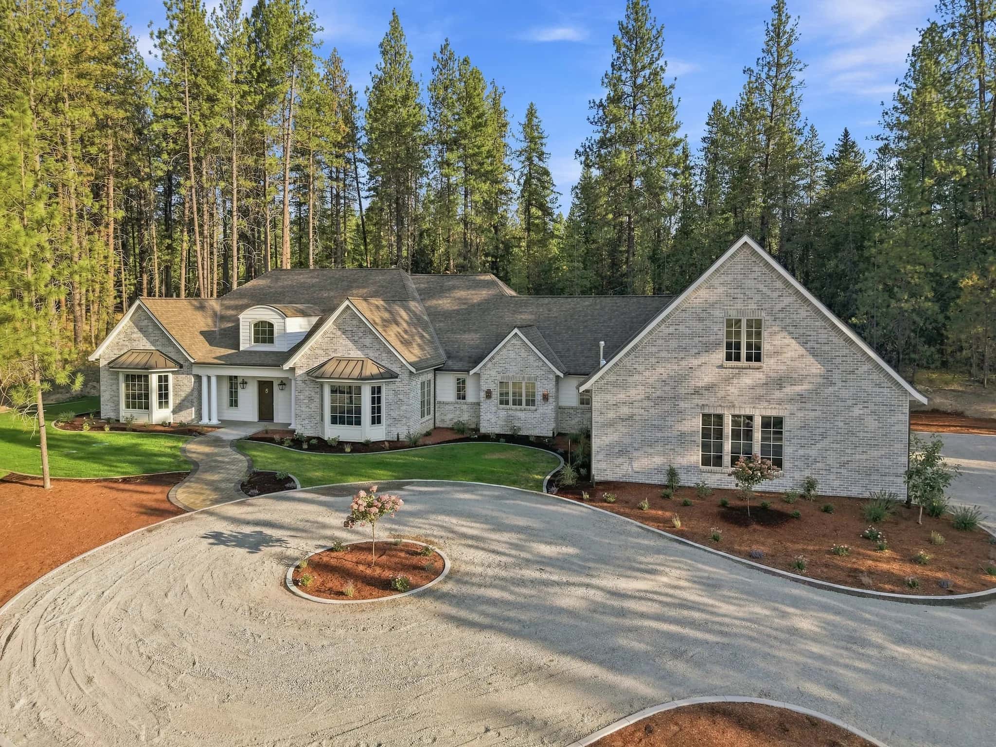 Aerial view of a JM Homes build and its circular drive on a wooded lot among tall pines