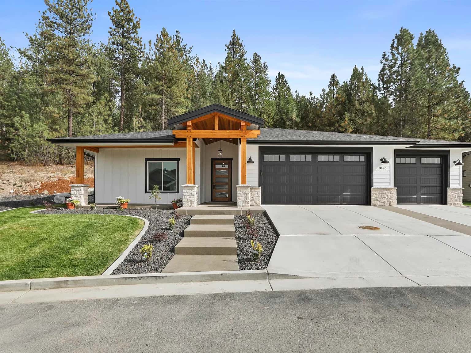 Single-story modern craftsman by JM Homes with a timber-framed entry and three-car garage