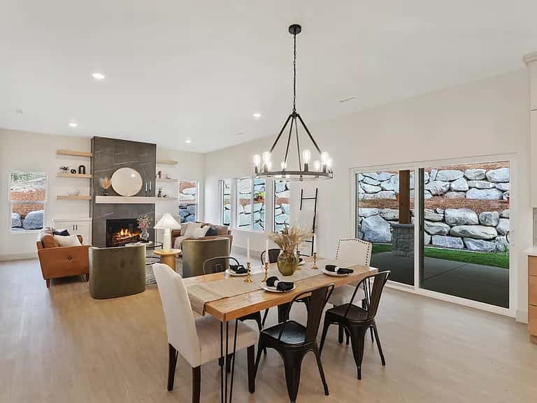 Open dining and living room with a farmhouse table and iron chandelier