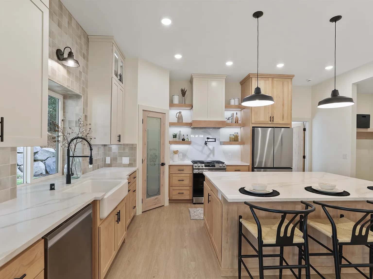 Maple and cream kitchen with a farmhouse sink, marble-look island and black pendants